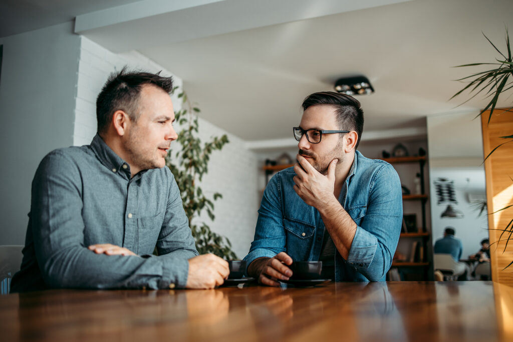 Men talking at a table while drinking coffee