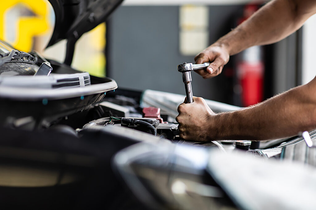 Hands holding a wrench working on a car engine